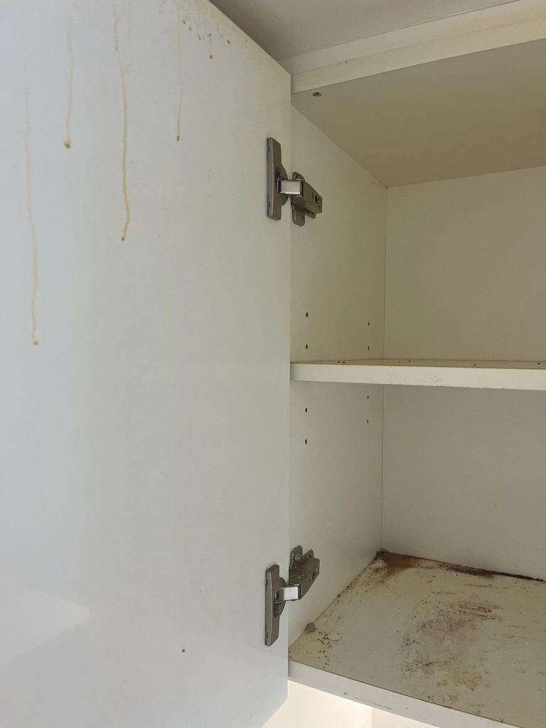 Grease buildup inside kitchen cabinets with visible stains and dirt on the surface, showing the need for a deep cleaning solution.